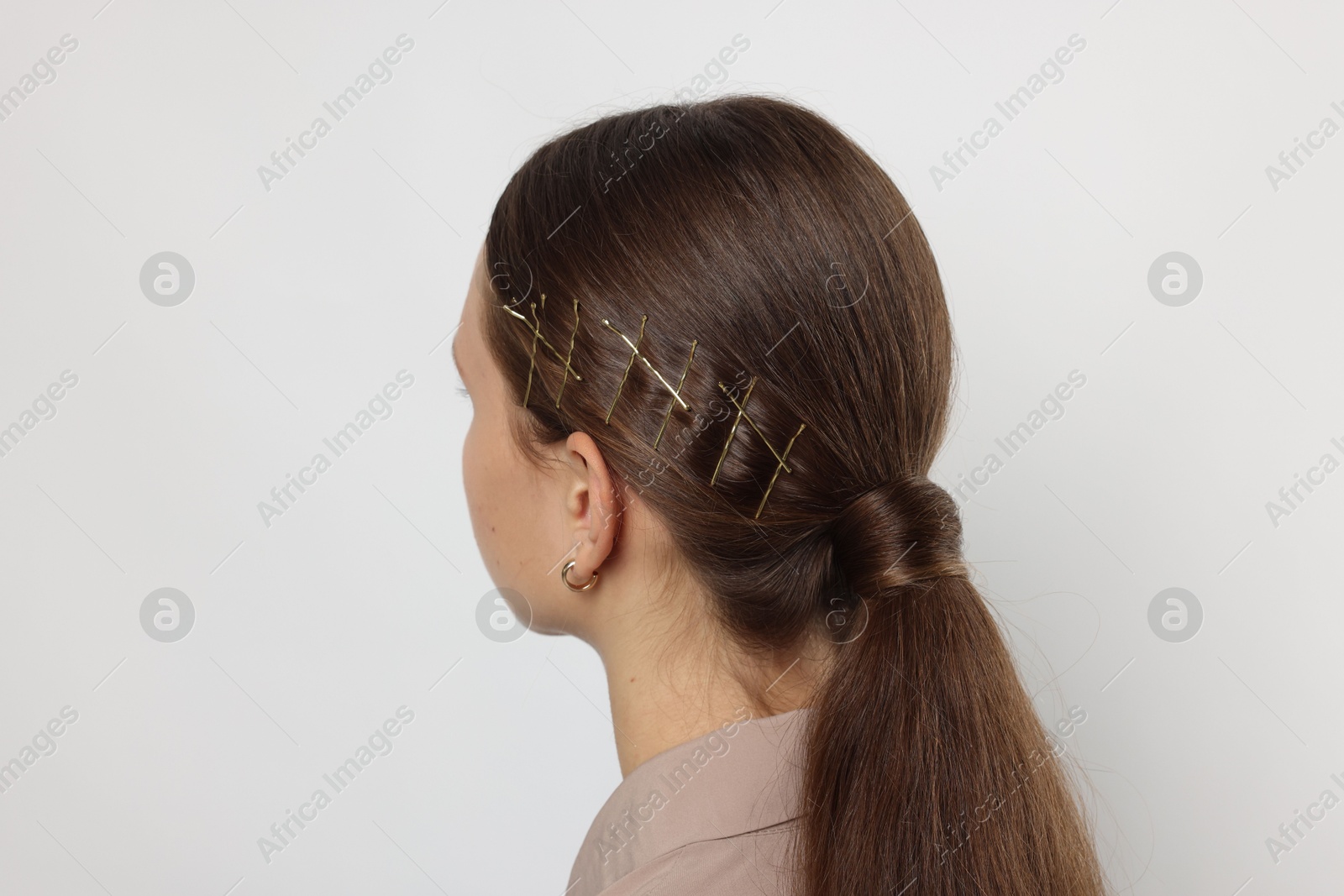 Photo of Teenage girl with stylish hair clips on white background, back view