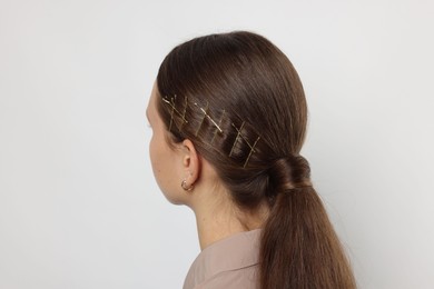 Teenage girl with stylish hair clips on white background, back view