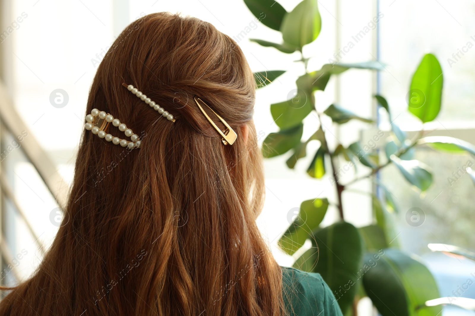 Photo of Teenage girl with stylish hair clips indoors, back view