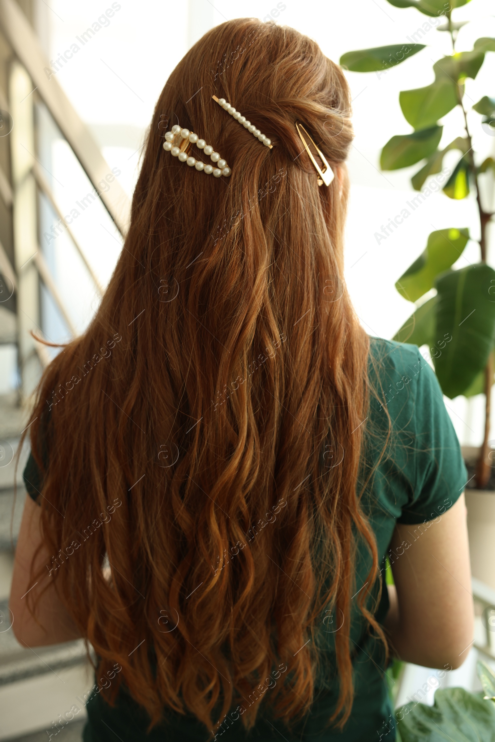 Photo of Teenage girl with stylish hair clips indoors, back view