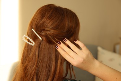 Photo of Teenage girl with stylish hair clips indoors, back view