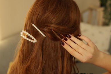 Photo of Teenage girl with stylish hair clips indoors, back view