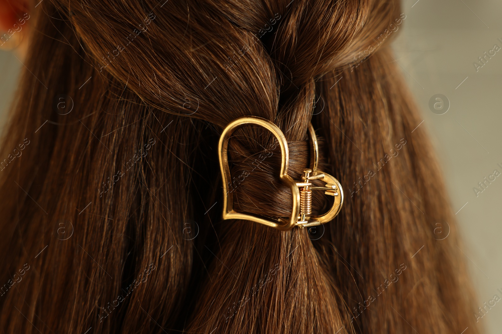 Photo of Teenage girl with stylish hair clip on blurred background, closeup