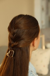 Photo of Teenage girl with stylish hair clip indoors, back view