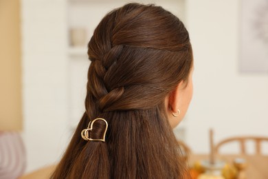 Photo of Teenage girl with stylish hair clip indoors, back view