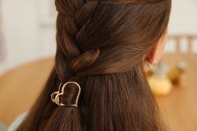 Photo of Teenage girl with stylish hair clip indoors, back view