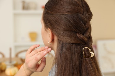 Photo of Teenage girl with stylish hair clip indoors, back view