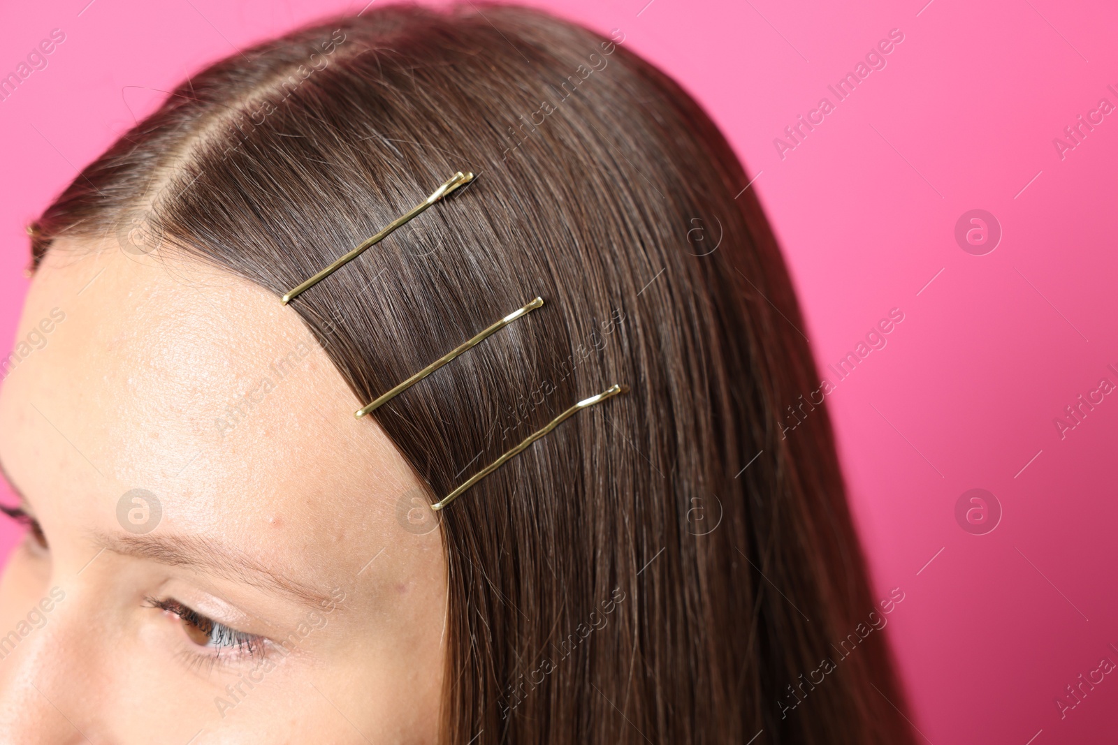 Photo of Teenage girl with stylish hair clips on pink background, closeup