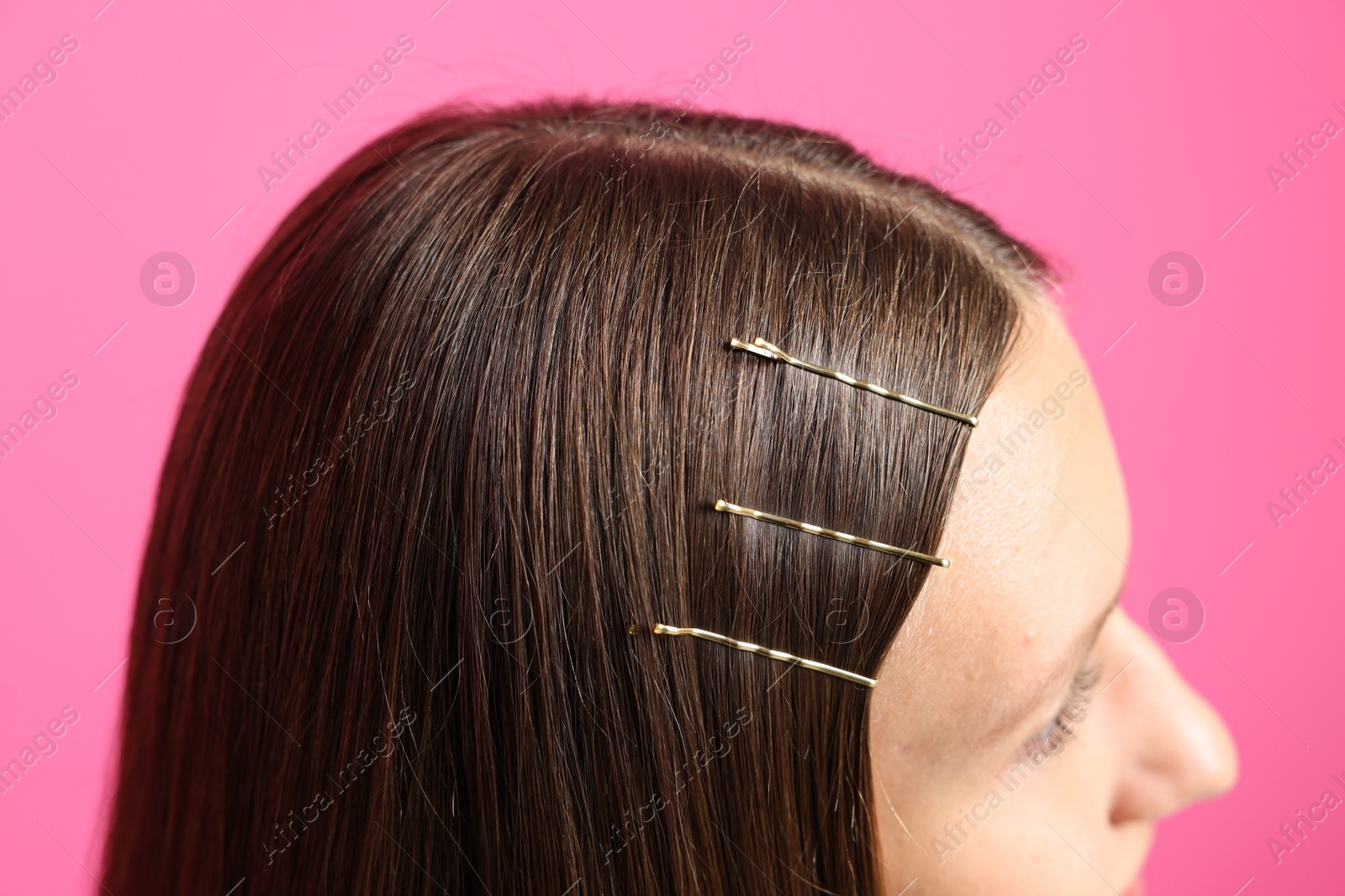 Photo of Teenage girl with stylish hair clips on pink background, closeup