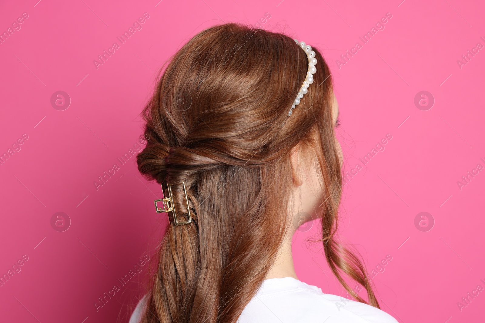 Photo of Teenage girl with stylish hair accessories on pink background, back view