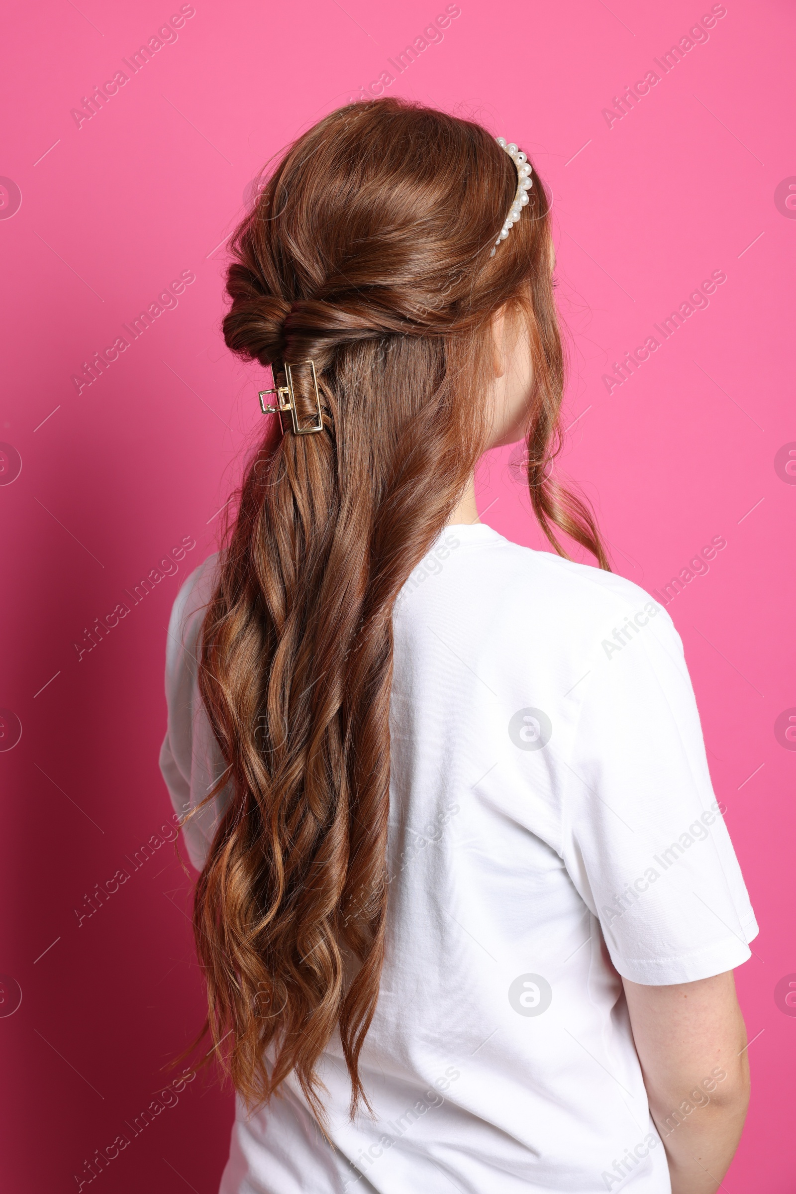 Photo of Teenage girl with stylish hair accessories on pink background, back view