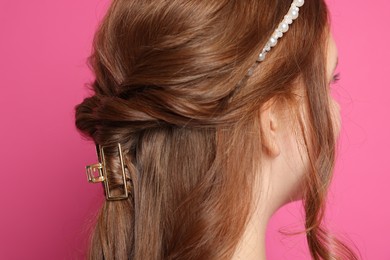 Photo of Teenage girl with stylish hair accessories on pink background, back view