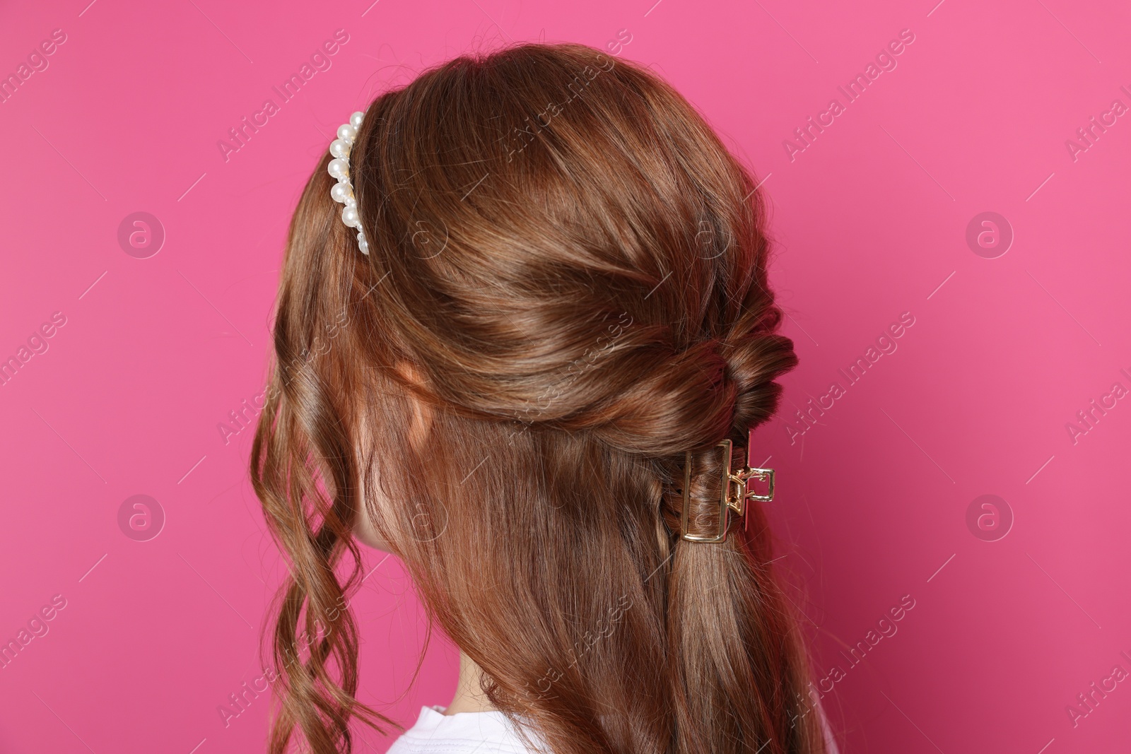 Photo of Teenage girl with stylish hair accessories on pink background, back view