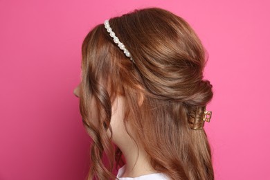 Photo of Teenage girl with stylish hair accessories on pink background, back view