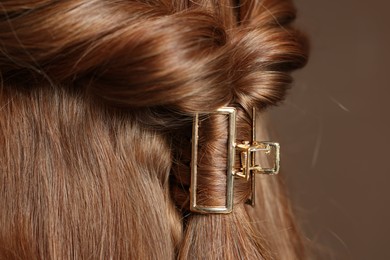 Photo of Teenage girl with stylish hair clip on brown background, closeup