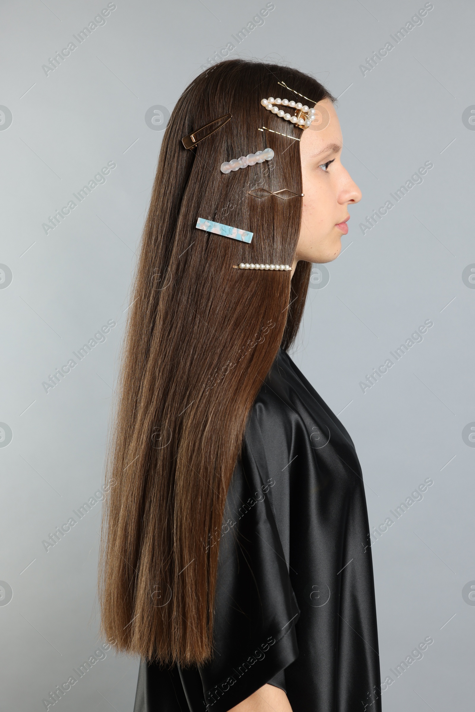 Photo of Teenage girl with stylish hair clips on light grey background