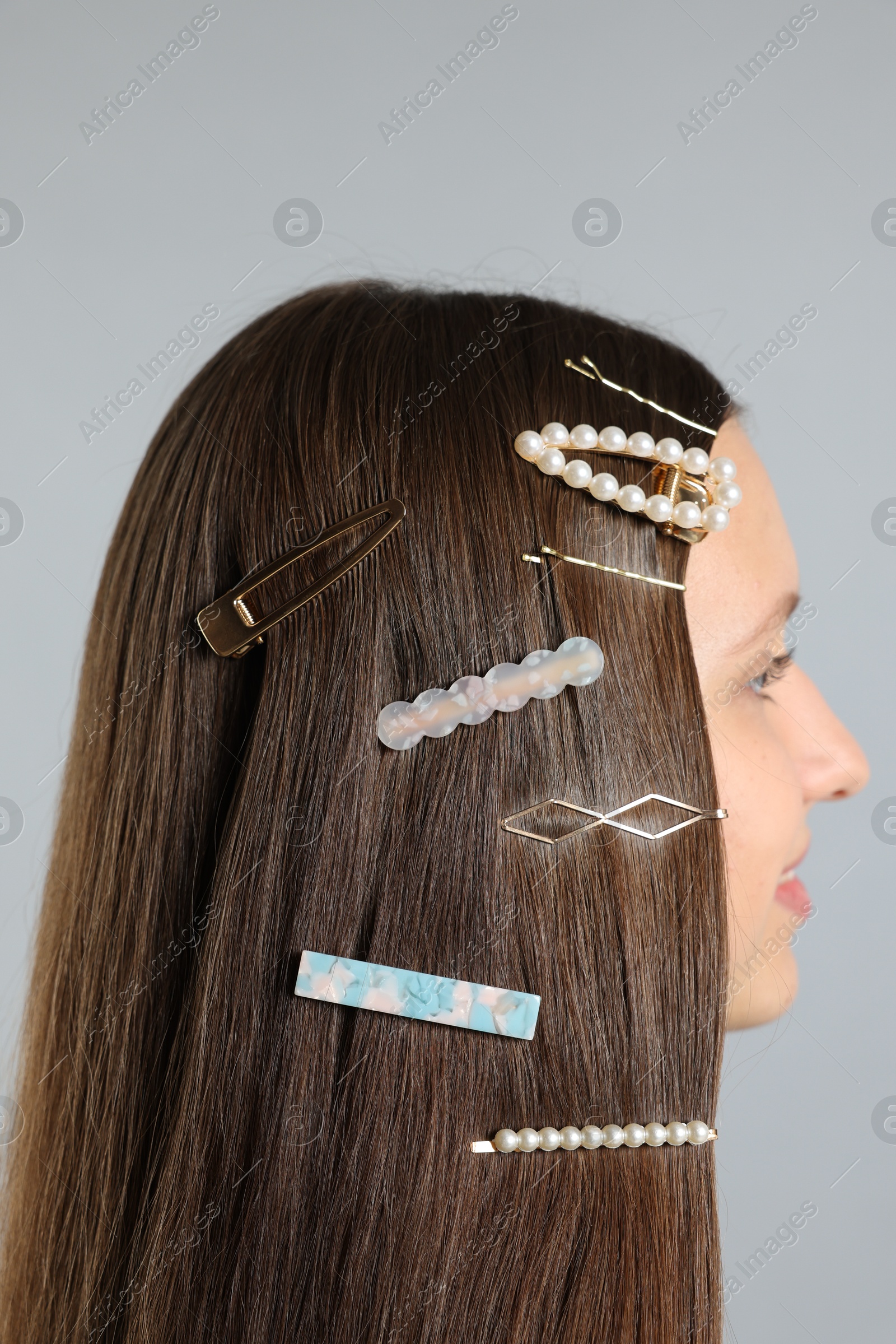 Photo of Teenage girl with stylish hair clips on light grey background, closeup