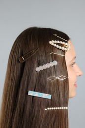 Photo of Teenage girl with stylish hair clips on light grey background, closeup