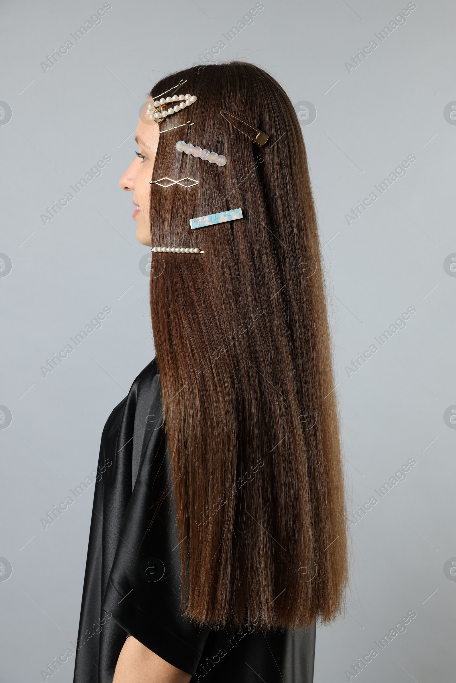 Photo of Teenage girl with stylish hair clips on light grey background