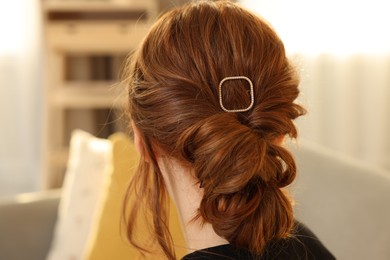 Photo of Teenage girl with stylish hair clip indoors, back view