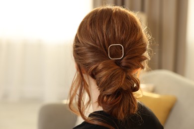 Teenage girl with stylish hair clip indoors, back view