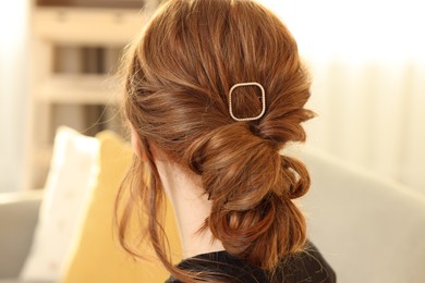 Photo of Teenage girl with stylish hair clip indoors, back view