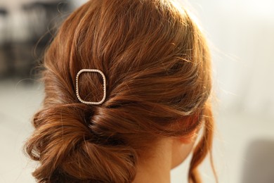 Teenage girl with stylish hair clip indoors, back view