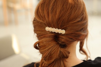 Photo of Teenage girl with stylish hair clip indoors, back view