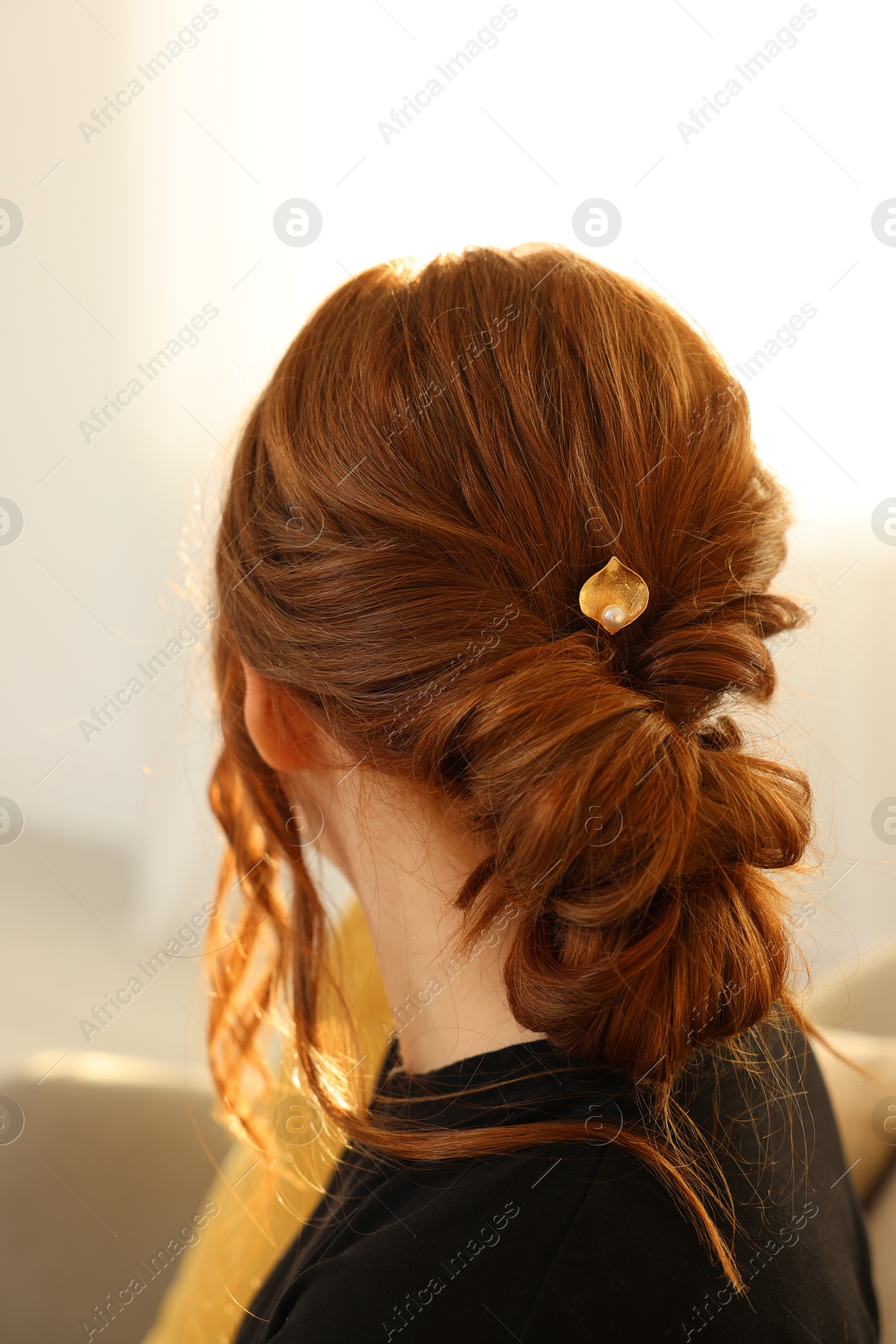 Photo of Teenage girl with stylish hair clip indoors, back view