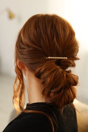 Photo of Teenage girl with stylish hair clip indoors, back view