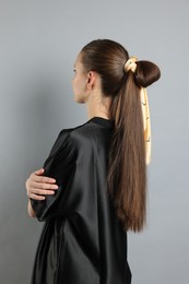 Photo of Teenage girl with stylish bandana on light grey background, back view