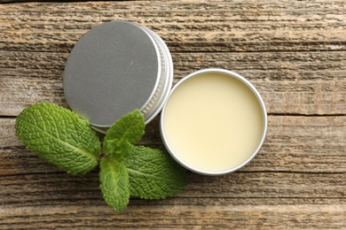 Photo of Natural lip balm and mint leaves on wooden background, top view