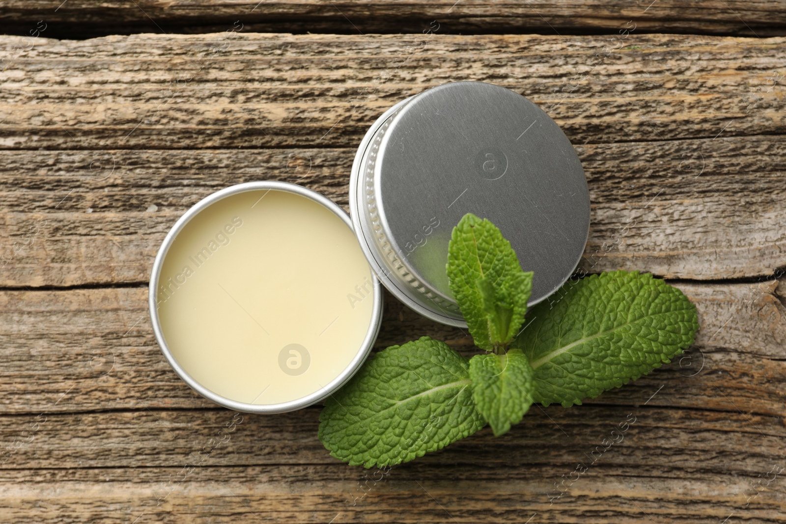 Photo of Natural lip balm and mint leaves on wooden background, top view