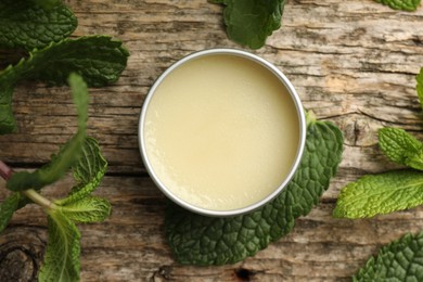 Photo of Natural lip balm and mint leaves on wooden background, flat lay