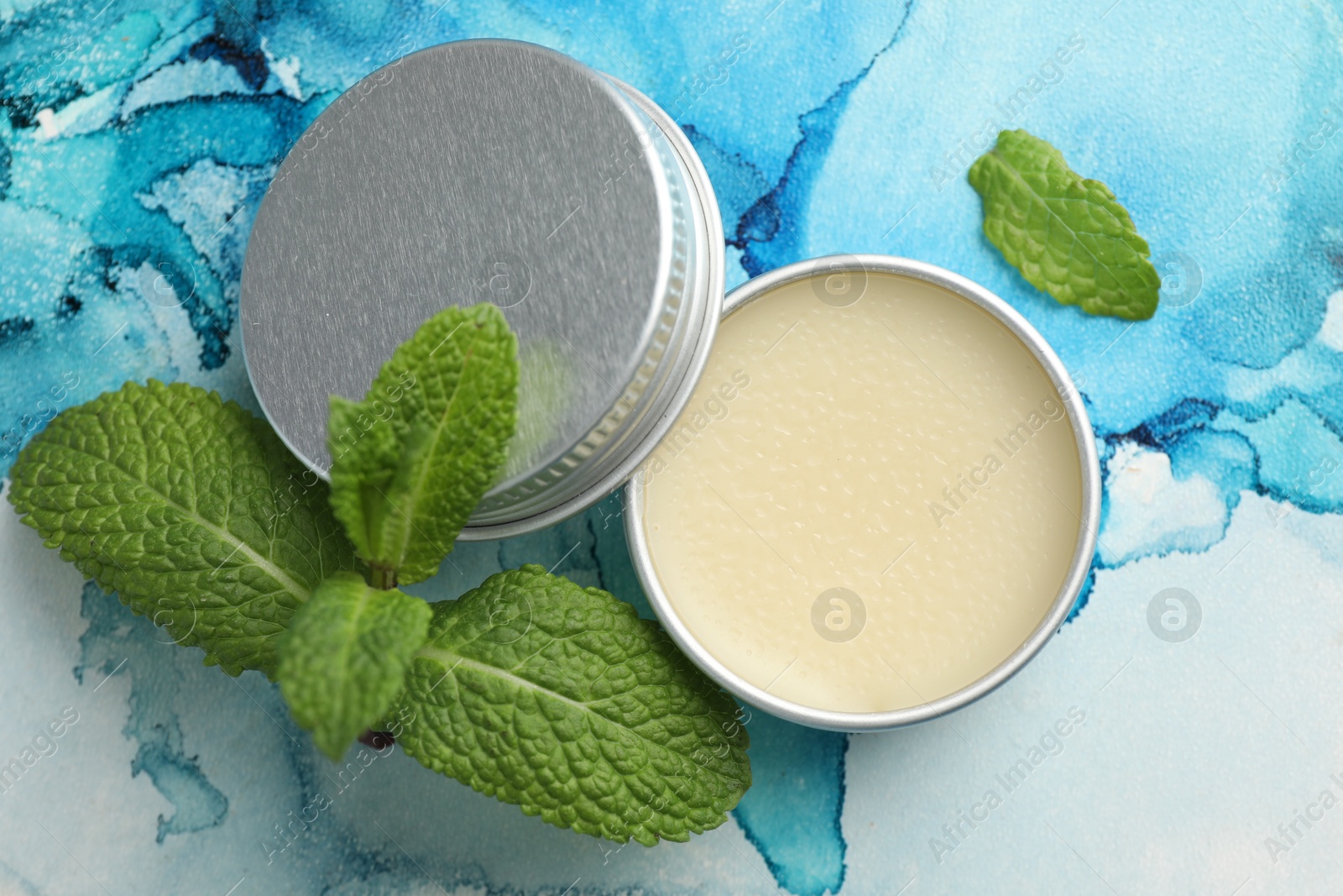 Photo of Natural lip balm and mint leaves on color background, top view