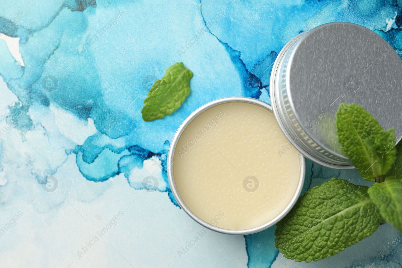 Photo of Natural lip balm and mint leaves on color background, top view. Space for text