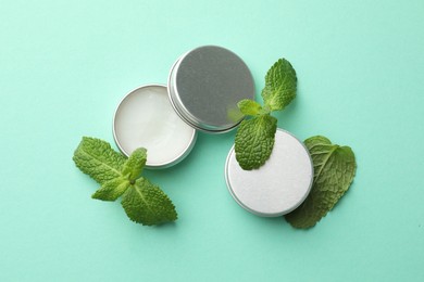 Photo of Natural lip balms and mint leaves on turquoise background, flat lay