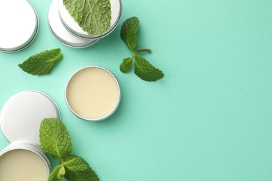 Photo of Natural lip balms and mint leaves on turquoise background, flat lay. Space for text