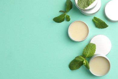 Photo of Natural lip balms and mint leaves on turquoise background, flat lay. Space for text