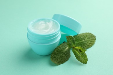 Photo of Natural lip balm and mint leaves on turquoise background, closeup