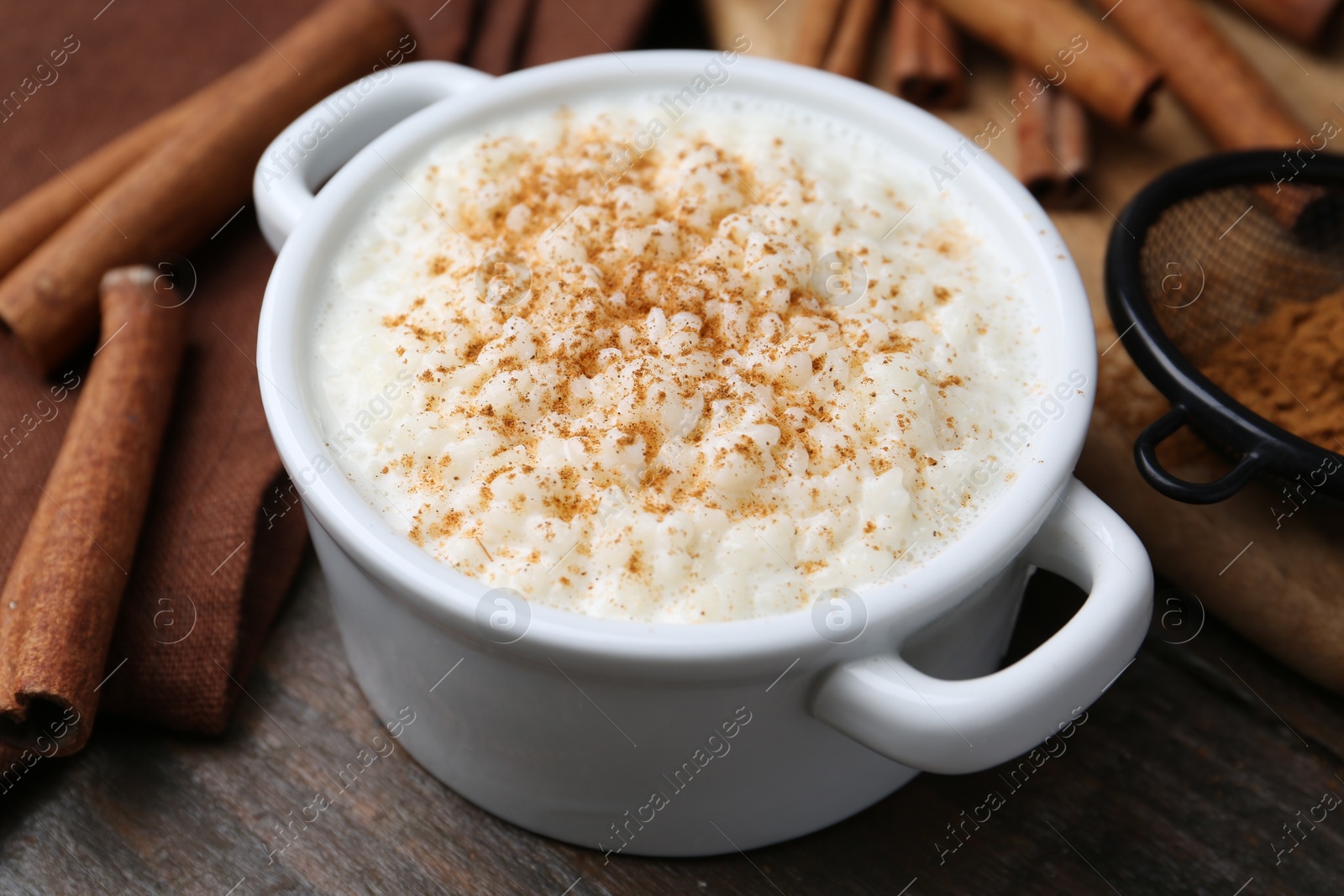 Photo of Delicious rice pudding with cinnamon on wooden table, closeup