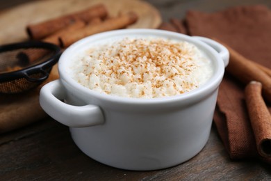 Photo of Delicious rice pudding with cinnamon on wooden table, closeup