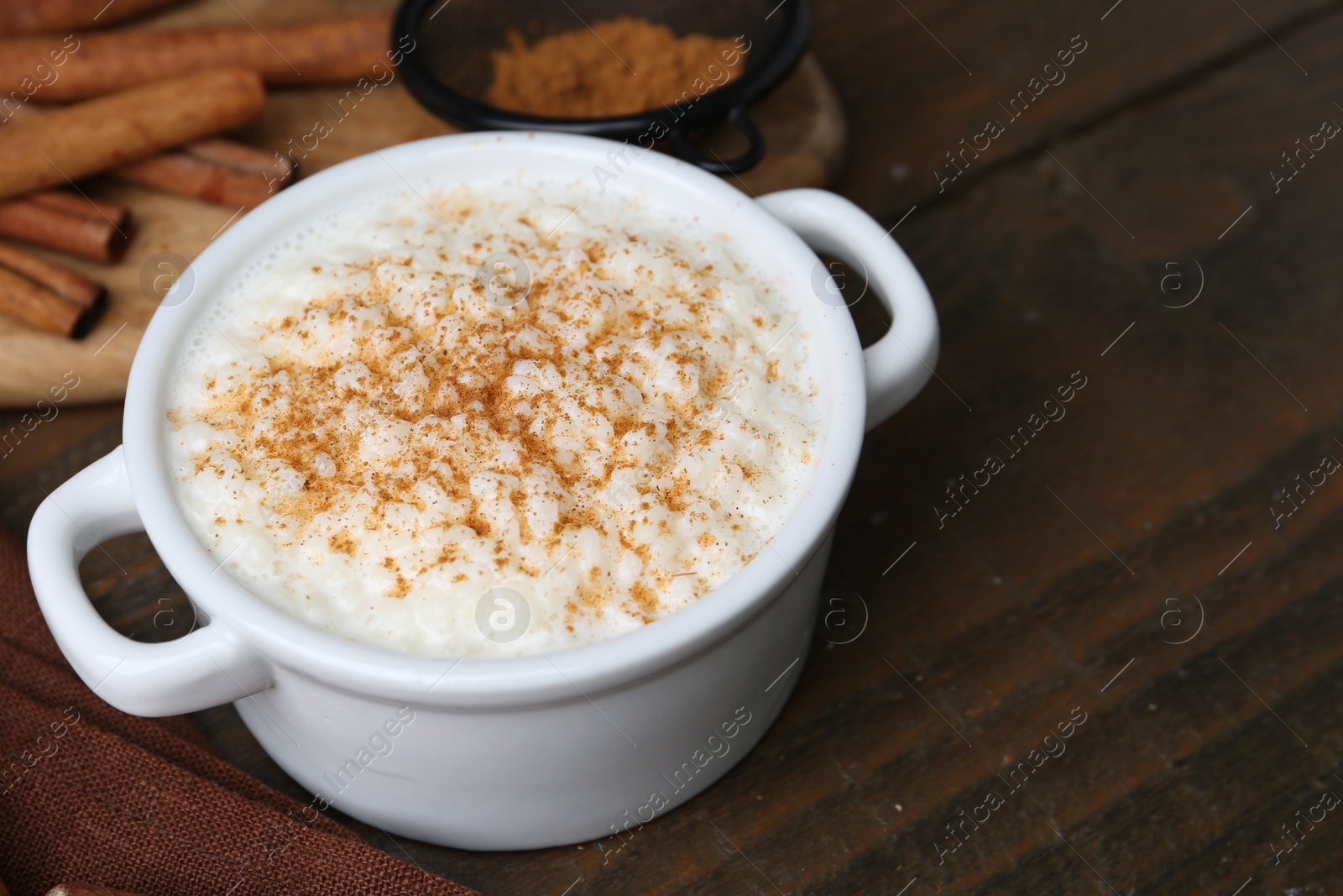 Photo of Delicious rice pudding with cinnamon on wooden table, closeup. Space for text