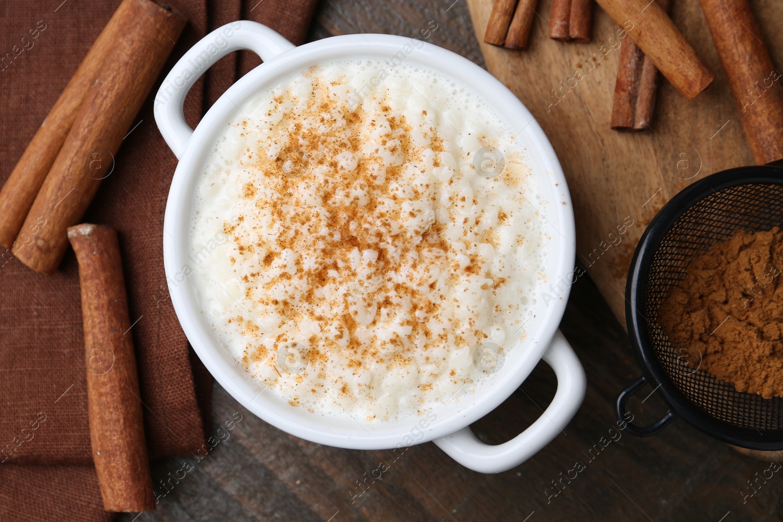 Photo of Delicious rice pudding with cinnamon on wooden table, flat lay