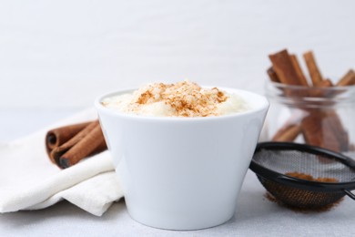 Photo of Delicious rice pudding with cinnamon on light table, closeup