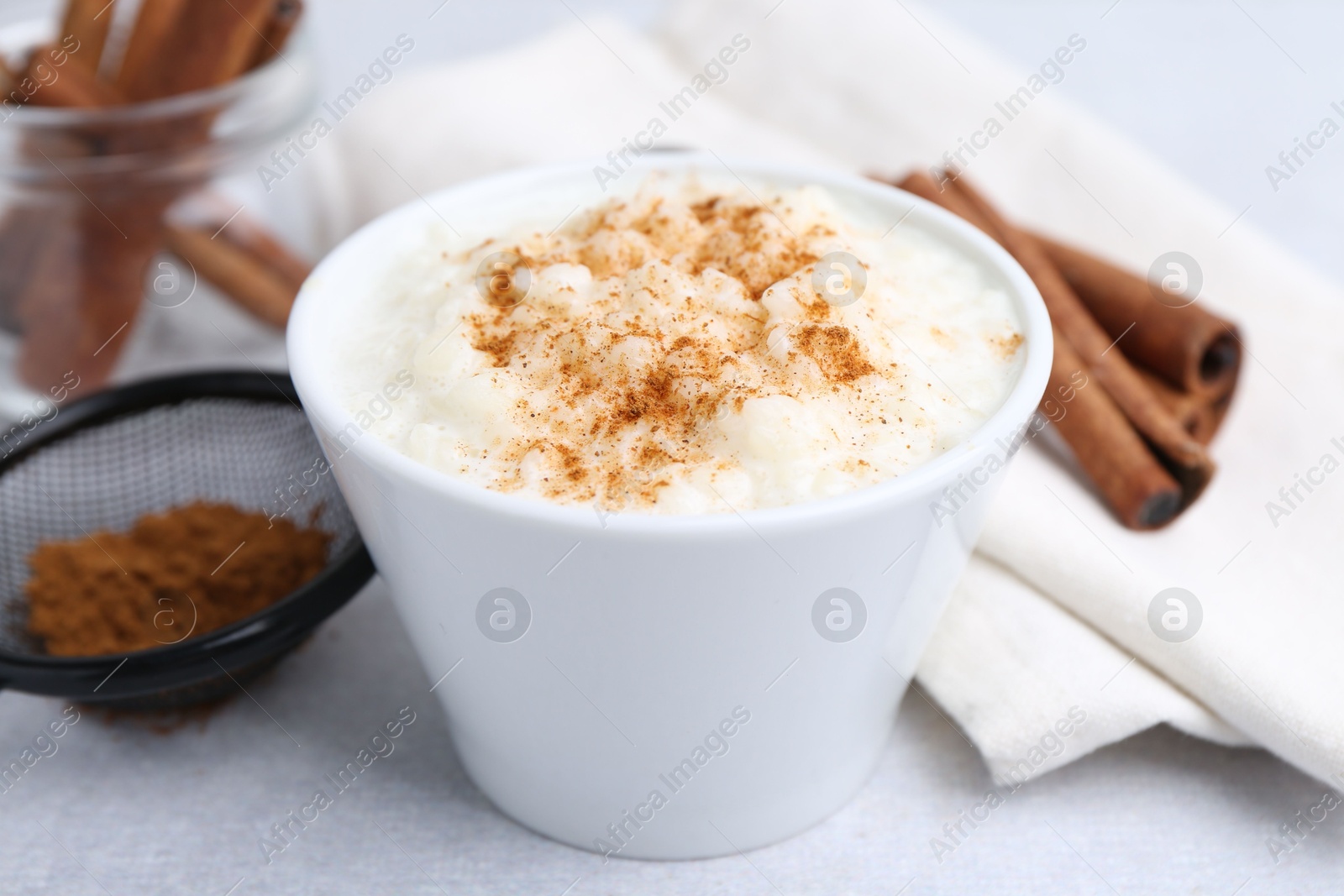 Photo of Delicious rice pudding with cinnamon on light table, closeup