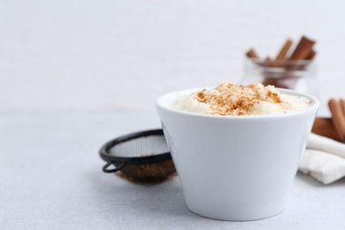 Photo of Delicious rice pudding with cinnamon on light table, closeup. Space for text