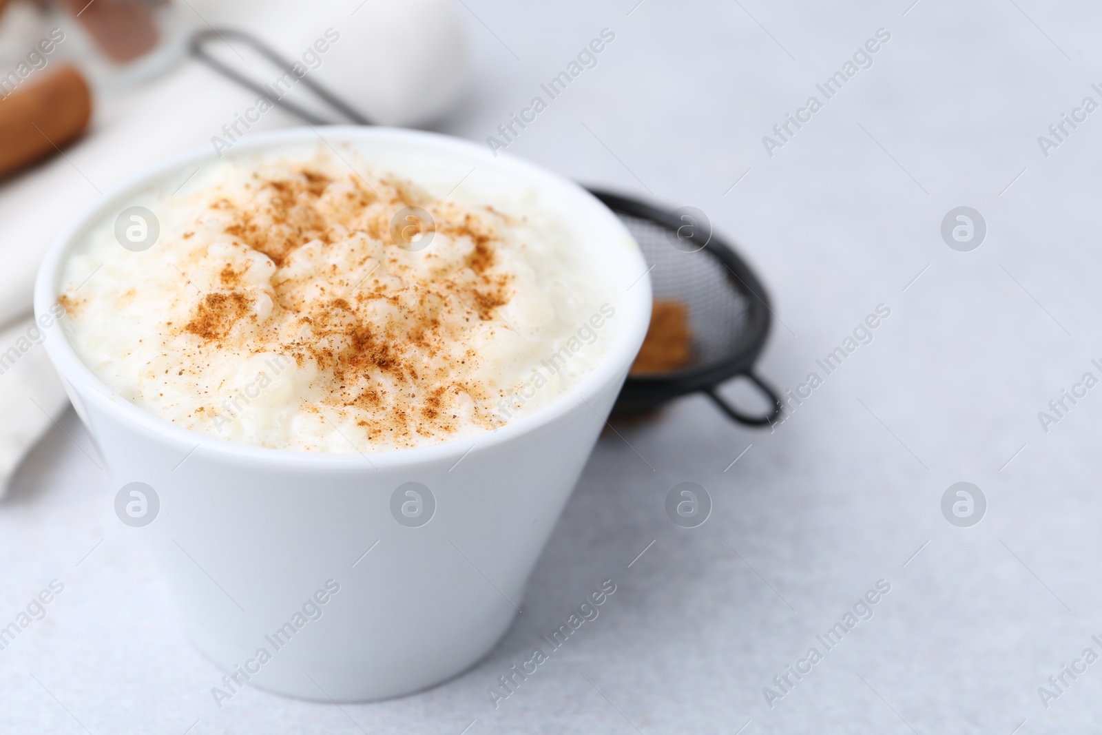 Photo of Delicious rice pudding with cinnamon on light table, closeup. Space for text