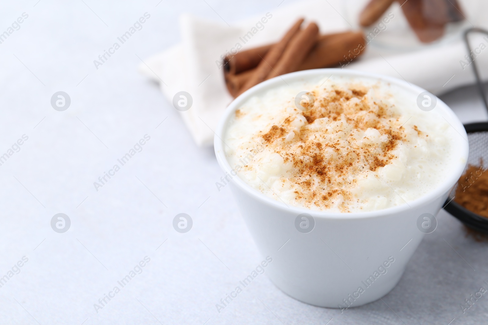 Photo of Delicious rice pudding with cinnamon on light table, closeup. Space for text