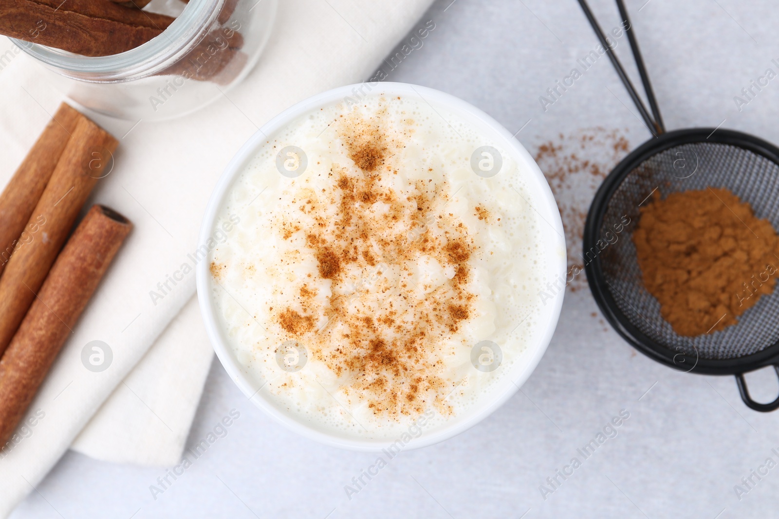 Photo of Delicious rice pudding with cinnamon on light table, flat lay